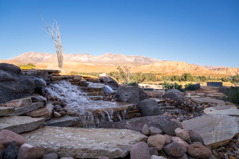 Flagstone stream and waterfall with boulders and river rock, red desert mountains in the background